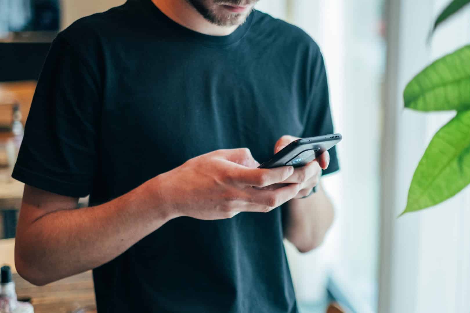 Mann sjekker regnskapet på mobilen